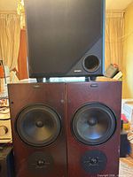 Front view of Jensen speaker atop two wood veneer bookshelf speakers