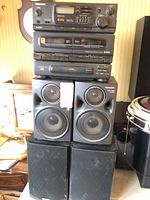 Stacked Panasonic stereo components atop two pairs of speakers