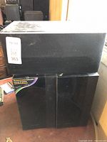 Rectangular subwoofer resting on two vertical Samsung cabinets