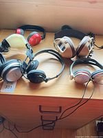 Group shot of five wired headphones on wooden surface