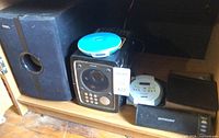 Shelf with Sony Walkman, Sanyo player, Philips unit, Coby speaker, remote