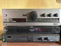 Front view of three stacked components showing Technics amplifier, Panasonic disc player, Braun player