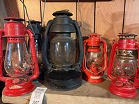 Five kerosene lanterns lined on shelf, showing overall lot