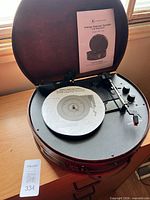 Turntable in open burgundy case with manual visible
