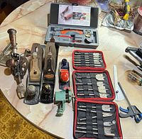 Table layout showing all tools: two bench planes, block plane, hand drill, staple gun, vise, soldering kit, bit set, spring clamp