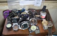 Group shot of all wristwatches, pocket watch, pedometer and accessories on wooden surface