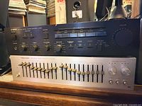 Front view of Yamaha A-500 amplifier stacked on Realistic graphic equalizer showing controls and sliders