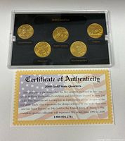 Front view of five gold-layered quarters in display case with certificate