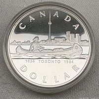Obverse of encapsulated 1984 Canadian silver dollar showing canoeist and Toronto skyline