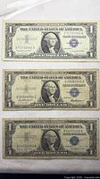 Obverse of three $1 silver certificates showing series years and blue seals