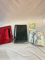 Group shot showing all five sealed tablet cases: red folio, black folio, two deer-print folios, clear cover
