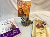 Overview of three Sylvia Browne paperbacks and ceramic bird figurine