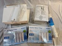 Overview of two pitcher filter boxes, loose plastic housing, Waterdrop filter and additional packaging