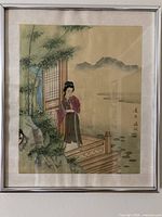 Framed watercolor on silk showing woman, bamboo and landscape
