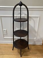 Front view showing full height, three tiers, arched top finial, wood tone.