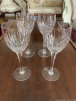 Four Stuart Monaco wine glasses standing on wooden surface