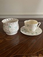 Teacup with saucer beside Millennium votive holder