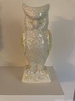 Front view of cream and yellow Belleek porcelain owl vase on square base