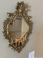 Full view of ornate gilt wood mirror mounted on wall