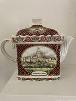 Left side view of teapot showing overall form, handle, spout and castle scene