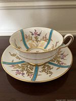 Side view of teacup on saucer showing pattern and gold trim