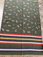 Full view of green scarf showing paisley design and striped border