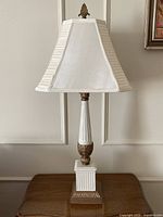 full view of lamp on table, showing porcelain column, plinth base, shade