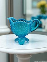 Pitcher front view showing shell and fan relief, applied handle, opalescent fade