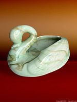 Front three-quarter view of green marbled slag glass swan planter