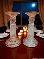 Both pink Depression glass candlestick holders on dining table lit by candles