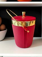 Full view of red ice bucket showing gold band, handle and knob