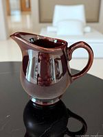 Right-side view of brown glazed pitcher showing handle, spout, and glossy finish