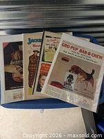 Four ads in protective sleeves on blue surface, Gro-Pup visible on top