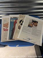 Group of four ads in protective sleeves on blue tote