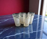 Four matching tumblers front view on dark marble surface