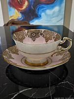 tea cup on saucer showing pink interior and gold lace pattern