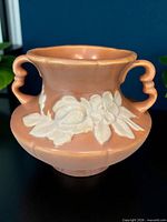 Front view showing peach glaze, white floral relief and both handles