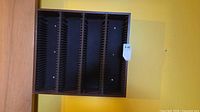 Front view of empty wall-mounted media rack showing four divider sections