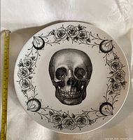 Front view of plate showing skull illustration, floral border, and tape measure indicating ~10.5 in diameter