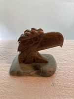 Front view of carved stone eagle head on base
