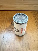 Paper-wrapped coin roll showing edge of stacked 1982 dollars