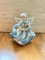 Front view of angel figurine showing dress, bird, flowers