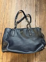 Full view of black leather Kate Spade tote showing shape, straps and exterior