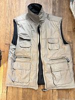 Front view of beige/tan vest showing zipper, stand collar, chest and lower pockets