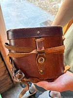 closed brown leather binocular case with strap and buckle