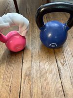 Pink 15-lb and blue 30-lb kettlebells side by side on wood floor