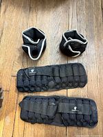 Top-down view of two ankle weights and two wrist weights on wooden floor