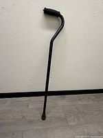 Full view of black metal adjustable walking cane with foam handle and rubber tip