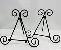 Two black scroll metal easels standing