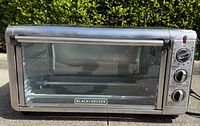 Front view of Black+Decker stainless steel toaster oven showing glass door and branding